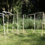 Een rijtje zeisen die in een grasveld staan