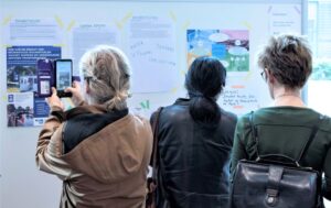 Een drietal mensen staat voor een display